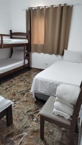a room with two beds and a table and a chair at Casa do Sol II in Peruíbe +23 photos