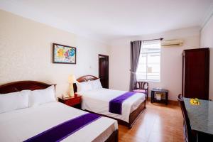 a hotel room with two beds and a table at Violet hotel&spa in Nha Trang