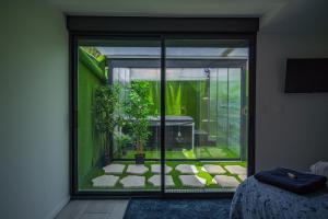 a room with a glass door with a garden outside at Capsule Océan 2 Chambres- Billard - Jacuzzi - Netflix in Valenciennes