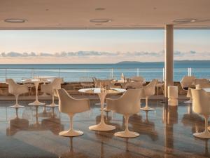 a restaurant with tables and chairs and a view of the ocean at Hôtel Les Roches - Relais & Châteaux in Le Lavandou