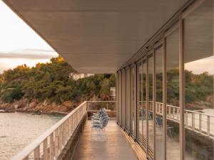 a balcony of a building with chairs and the water at Hôtel Les Roches - Relais & Châteaux in Le Lavandou