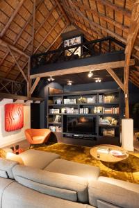 a living room with a couch and a tv at Luxe Veluwse Bosrand Suite met Jacuzzi en Zwembad in Lunteren