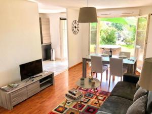 a living room with a couch and a tv and a table at Le Grasberg in Bergheim