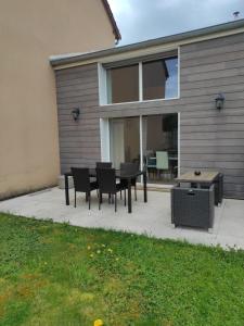 a patio with a table and chairs and a grill at Maison en sortie d'autoroute A31 in Rolampont