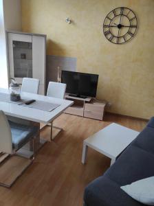 a living room with a table and a clock on the wall at Maison en sortie d'autoroute A31 in Rolampont