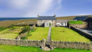 an old house with a stone wall next to the ocean at Orkney Retreats Island Farmhouses & Cottages in Sanday