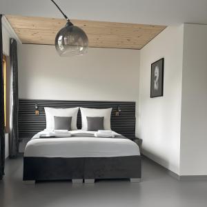 a white bedroom with a large bed and a lamp at RS Boardinghouse Aparthotel mit Charme und Hotelservice in St. Gallen