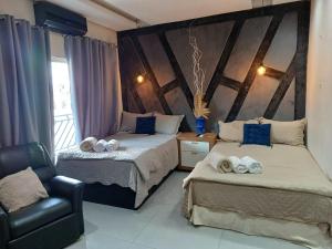 a bedroom with two beds and a chair and a window at Loft dos sonhos cobertura in Boa Vista
