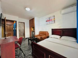 a bedroom with a bed and a desk and a chair at CAMERHOME "Low Cost" in Douala