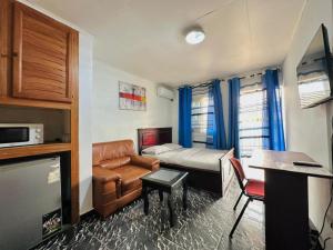 a bedroom with a bed and a couch and a desk at CAMERHOME "Low Cost" in Douala