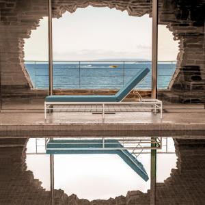 a bench in front of a window with the ocean at Hôtel Les Roches - Relais & Châteaux in Le Lavandou