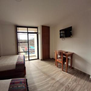 a hotel room with a desk and a bed and a table at Hotel San Marcos Las Lajas in Ipiales