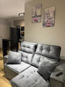 a leather couch in a living room with a kitchen at Apê 64 Bela Vista com ar condicionado e garagem in Espirito Santo Do Pinhal