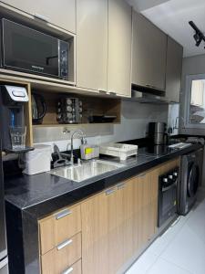 a kitchen with a sink and a microwave at Apê 64 Bela Vista com ar condicionado e garagem in Espirito Santo Do Pinhal