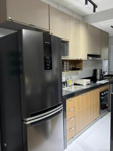 a kitchen with a stainless steel refrigerator and wooden cabinets at Apê 64 Bela Vista com ar condicionado e garagem in Espirito Santo Do Pinhal +28 photos