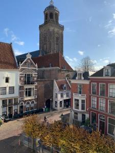 a group of buildings with a clock tower in the background at Kleinschalig Hostel in Deventer, centrum stad, aan de IJssel, in Deventer