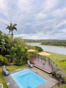 an outdoor pool with chairs and umbrellas next to a river at Bonza Bay Bliss in East London