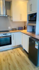 a kitchen with white cabinets and a black refrigerator at Bonza Bay Bliss in East London