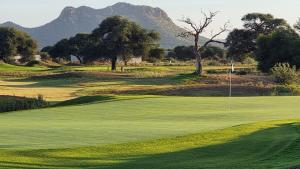 a green golf course with a mountain in the background at Stay at 64 Omeya in Windhoek