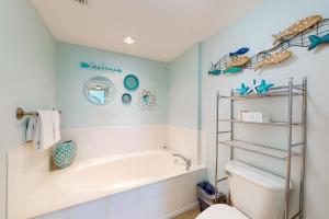 a bathroom with a tub and a toilet at Paradise Shores 305 in Mexico Beach +24 photos