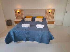 a bedroom with a blue bed with towels on it at Casa Rosinha, views & sunset in Calheta