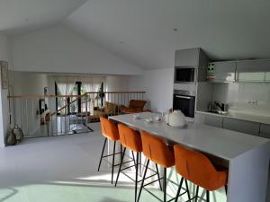a kitchen with a bar with orange chairs in it at Casa Rosinha, views & sunset in Calheta