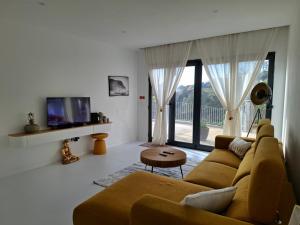 a living room with a couch and a tv at Casa Rosinha, views & sunset in Calheta