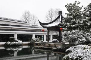 a pavilion in a garden with a pond in front of a building at Jinling Resort Nanjing in Nanjing
