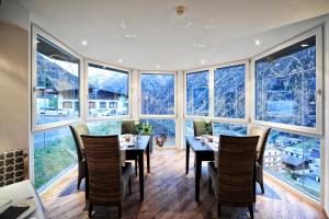 a dining room with a table and chairs and windows at Alp Resort Tiroler Adler in Sölden