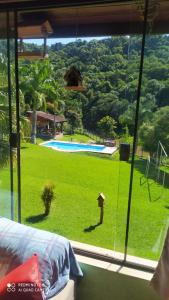 a room with a window with a view of a yard at Chacára Reni in Itajubá +2 photos