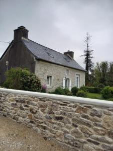a stone house behind a stone retaining wall at La maison de Yo in La Feuillée