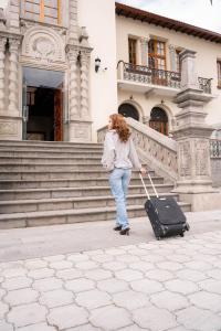 a woman walking with a suitcase in front of a building at Hotel Boutique Circasiana Palace in Quito