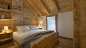 a bedroom with a bed with wooden walls and a window at Chalet Les Combes in Ponte di Legno