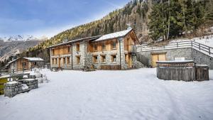a large building with snow in front of a mountain at Chalet Les Combes in Ponte di Legno