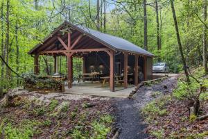a wooden pavilion in the woods with a car parked at A-Frames Under the Canopy - Multi-Cabin Retreat in Pine Ridge