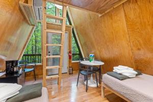a room with two beds and a table and a window at A-Frames Under the Canopy - Multi-Cabin Retreat in Pine Ridge