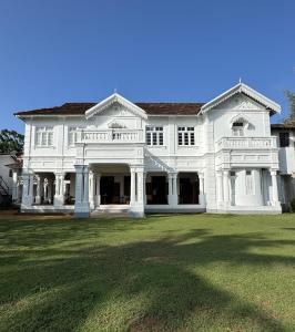a large white house with a large yard at Villa de Zoysa Yoga, Wellness & Waves in Busse