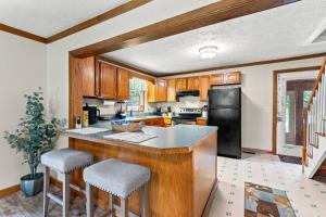 a kitchen with wooden cabinets and a black refrigerator at Hidden Treasure- Private Pool, Pond, 1600 Acres in Clay City