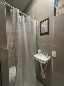 a bathroom with a shower curtain and a sink at Suíte Neblina in Garanhuns