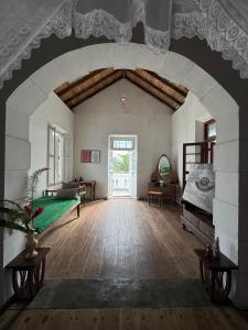 a large room with a green bed and an archway at Villa de Zoysa Yoga, Wellness & Waves in Busse