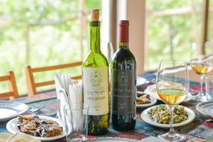 a table with two bottles of wine and plates of food at dimis ferdobi in Dimi