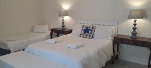 a bedroom with two beds with white sheets and lamps at Jetty Self-Catering in Swakopmund