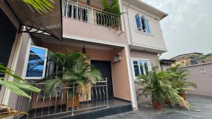 a house with palm trees in front of it at SEGXYCOLD VALLEY OASIS Elegant 2-Bedroom Apartment in Agege +8 photos