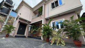 a house with palm trees in front of it at SEGXYCOLD VALLEY OASIS Elegant 2-Bedroom Apartment in Agege