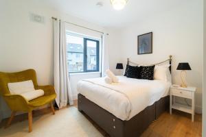 a bedroom with a bed and a chair and a window at Renada Cottage - Dingle Town Centre in Dingle