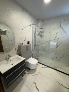 a white bathroom with a toilet and a sink at Villa Rosa Luxury Boutique Hotel in Batroûn