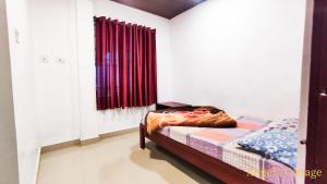 a bedroom with a bed and a window with curtains at Angel's Cottage in Munnar
