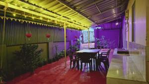 a dining room with a table and chairs and purple lighting at Angel's Cottage in Munnar