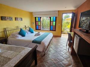 a bedroom with two beds and a tv and windows at La Primavera, casas campestres para familias, paisajes, tranquilidad, cerca al pueblo in Villa de Leyva