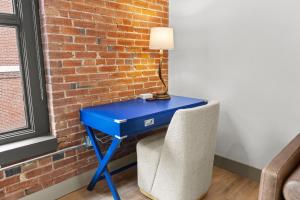 a blue desk with a chair next to a brick wall at Brick & Bed Riverfront Lofts, T 305 in Saint Louis